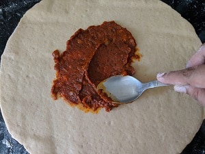 spreading pizza sauce for rolls