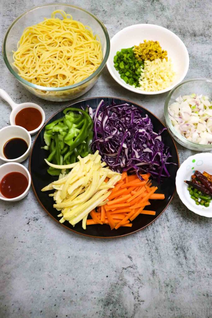 Cooked spaghetti, vegetables, condiments, chillies, onion, garlic and scallions