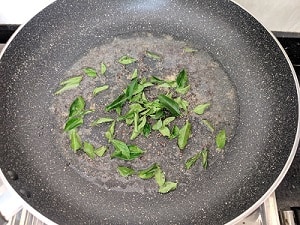 pan with coconut oil, mustard seeds and curry leaves to make Mezhukkupuratti
