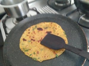Cooking the flatbreads with ghee on a hot griddle.