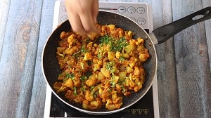 garnishing aloo gobi with finely chopped coriander
