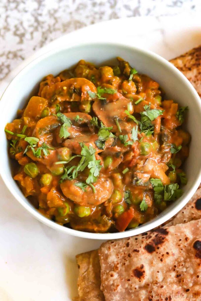 Close up view of Mushroom Masala with peas garnished with coriander