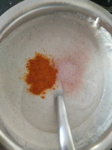 Adding salt and turmeric to the Surnoli batter