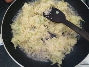 Cooking the raw grated mangoes in mustard seeds and oil