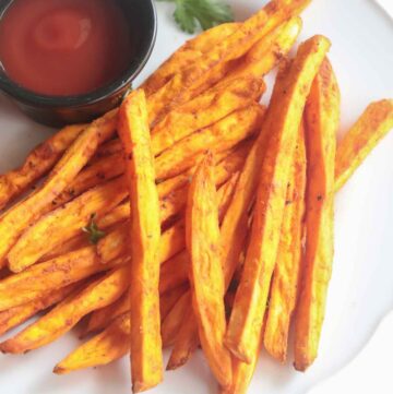 crispy sweet potato fries served with tomato ketchup in a white plate