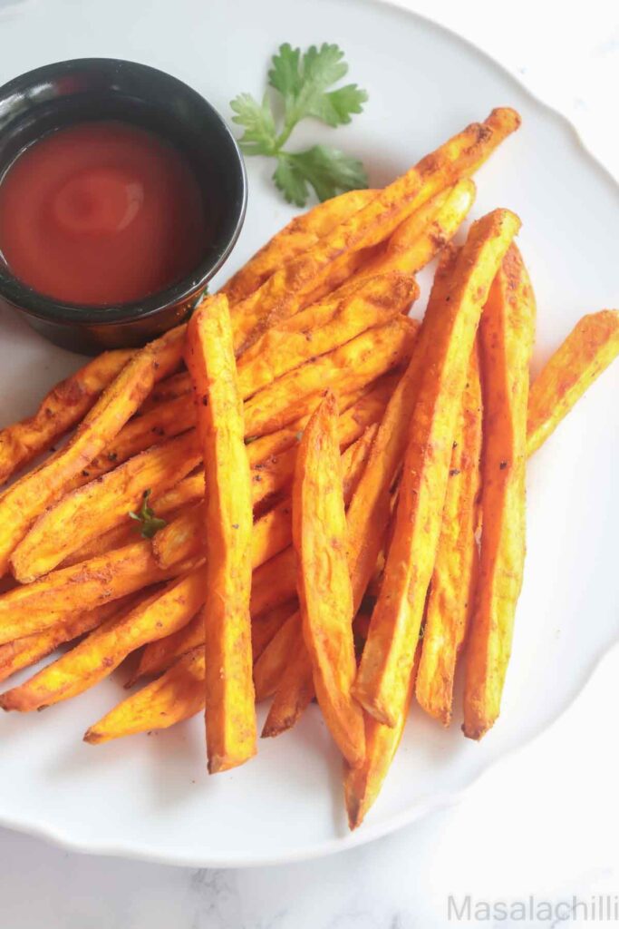 crispy sweet potato fries served with tomato ketchup in a white plate
