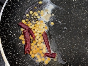 tempering of mustard seeds, chana dal and dry red chillies for tomato raita