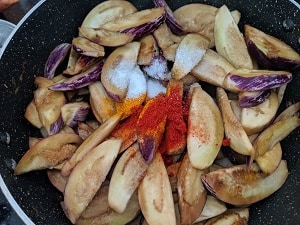 Adding seasoning to the brinjal slices