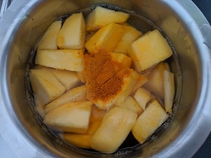 Add turmeric powder to the mangoes and cook