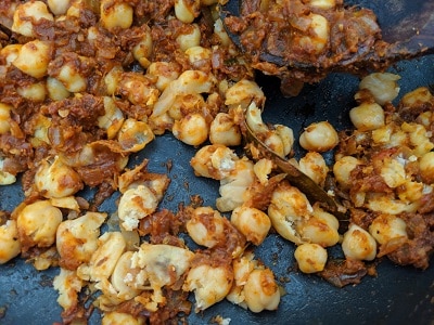 Mashing the chickpeas to thicken the gravy