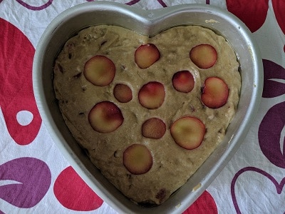Decorating the sliced fresh plums on the cake