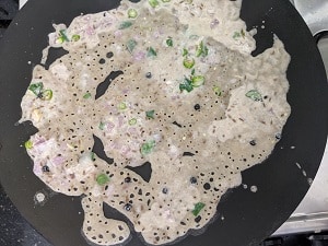 Ragi Rava Dosa cooking on a hot griddle