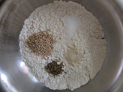 Adding salt, sesame seeds, ajwain, hing to the flours