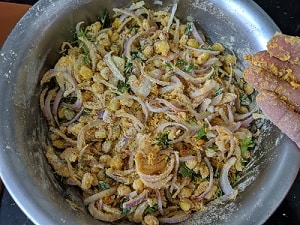 Lightly pressing the onions so that they release the juice which leads to crispier pakodas