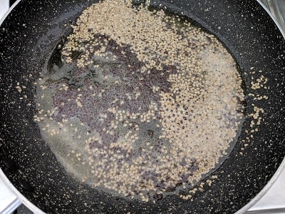 Pan with oil, mustard seeds, sesame seeds and hing as tempering for the alu vadi recipe