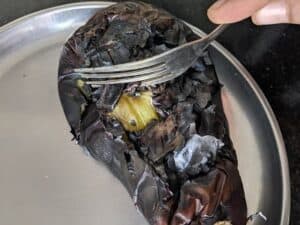 Scraping the skin of the roasted eggplant for the chutney