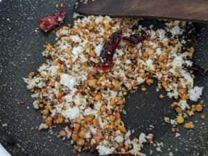 Coconut added to the roasted lentils and dry red chillies