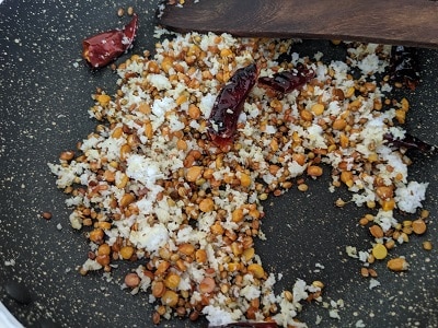Adding grated coconut to the roasted lentil mix