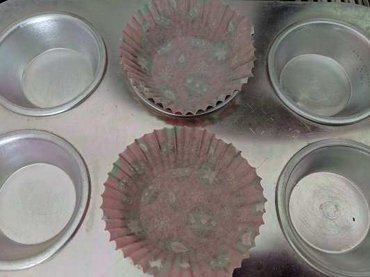 Preparing the muffin tray by lining with muffin liners