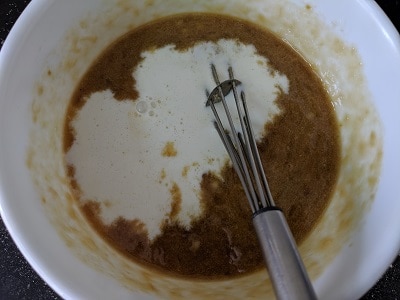 Adding milk and vanilla essence to the jaggery and mashed bananas