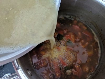 Adding the cooked lentils to the tamarind broth