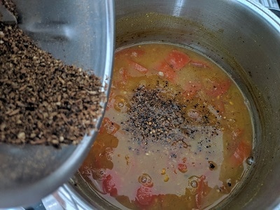 adding the freshly ground spices to the reduced tamarind broth