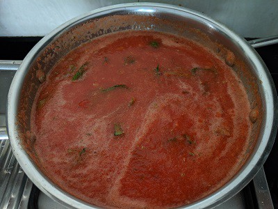 Cooking the pizza sauce until it thickens