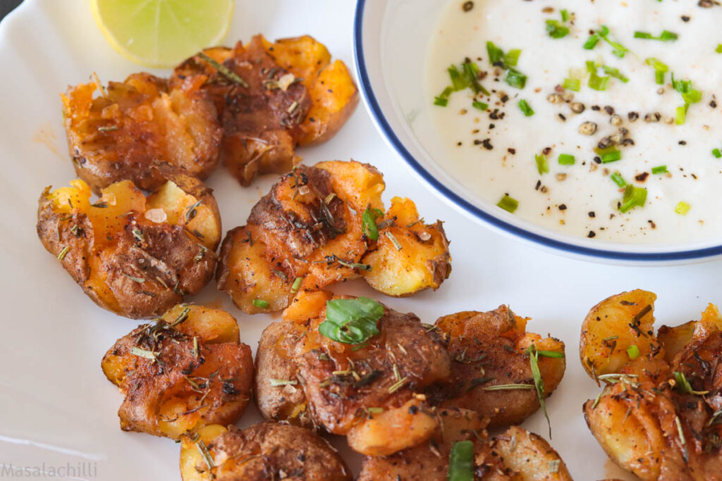White plate filled with baked and Smashed potatoes served with garlic labneh