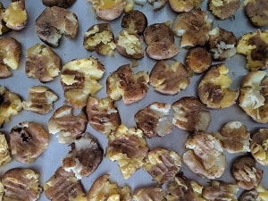 Smashed potatoes lined on a baking tray