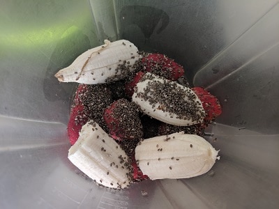 Blender jar with roughly chopped banana, strawberries, honey and chia seeds