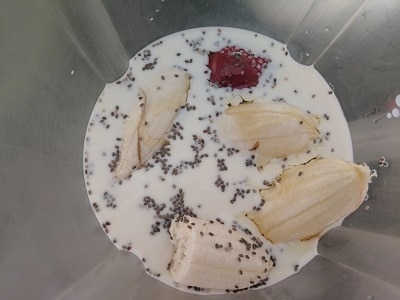 Milk added to the blender jar along with strawberry, banana and chia seeds