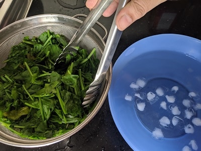 Shocking the spinach leaves by adding to cold water