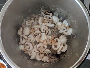 adding sliced mushrooms to the onion and spices