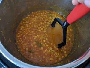 Mashing the dal slightly for thick creamy consistency