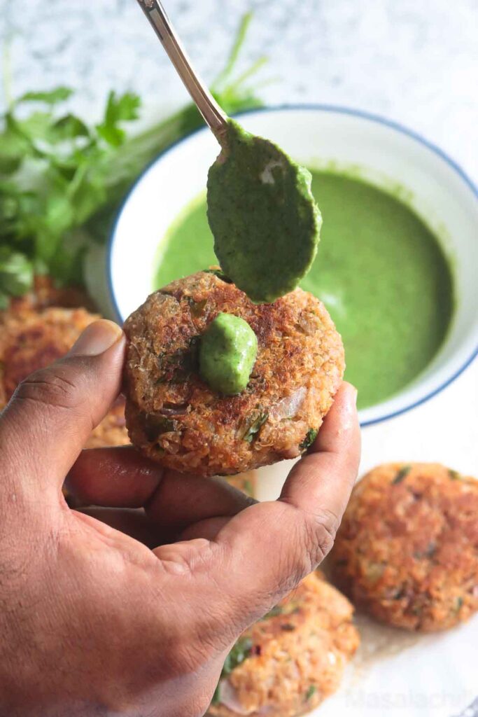 Holding a portion of Quinoa patties topped with cilantro mint yogurt sauce