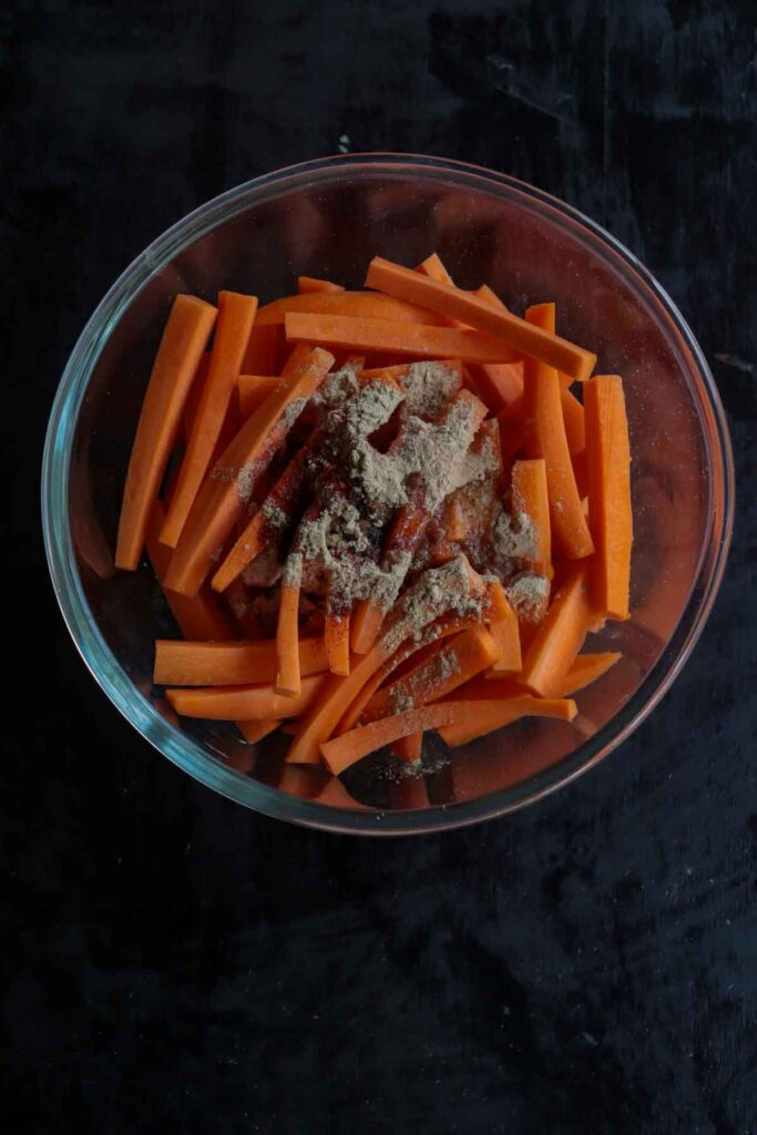 Seasoning the carrots with spices and oil