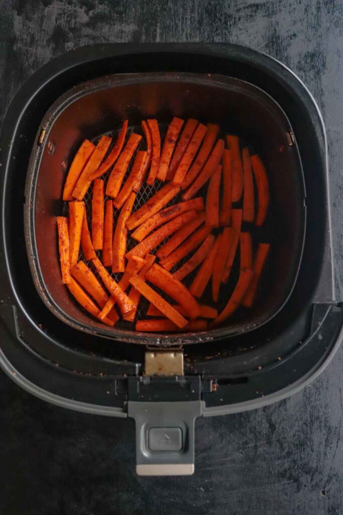 Arranging the carrot sticks for even cooking in the air fryer basket