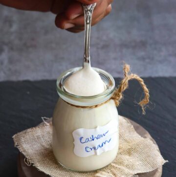 Spoonful of cashew cream taken from a glass jar
