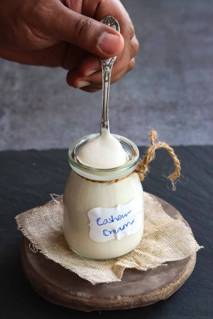 Spoonful of cashew cream taken from a glass jar
