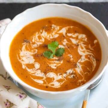 White bowl with Tomato Soup garnished with cashew cream