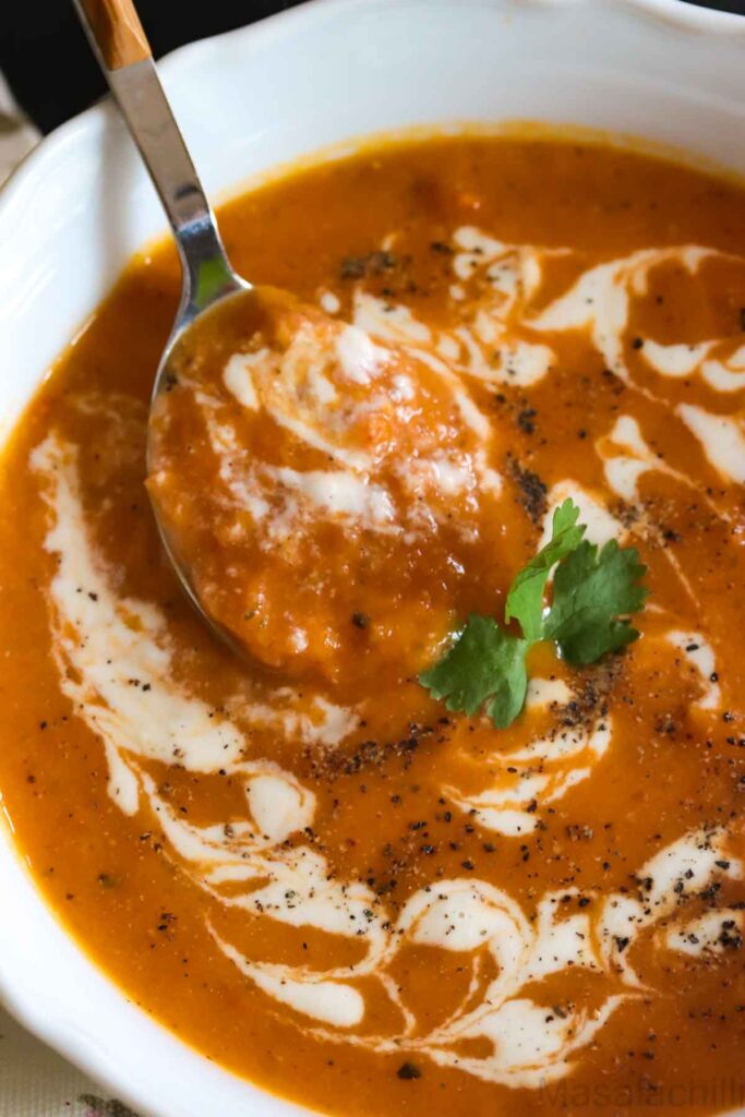Close up view of tomato bisque garnished with cream and black pepper