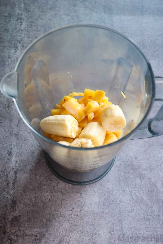 Blender jar with banana, pineapple, coconut milk and honey