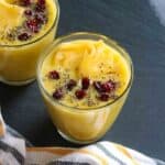 Glass with pina colada smoothie topped with chia, cranberries and pineapple slice