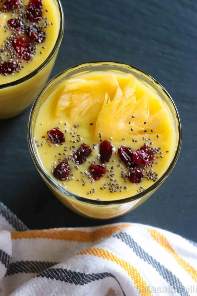 close up view of pina colada smoothie topped with chia, cranberries and pineapple slice