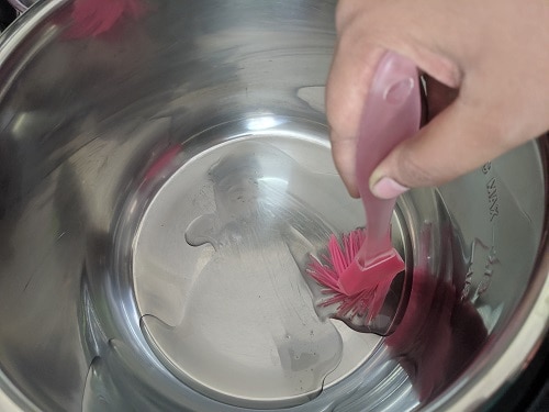 Applying oil to the steel insert of the inner pot to place kneaded dough