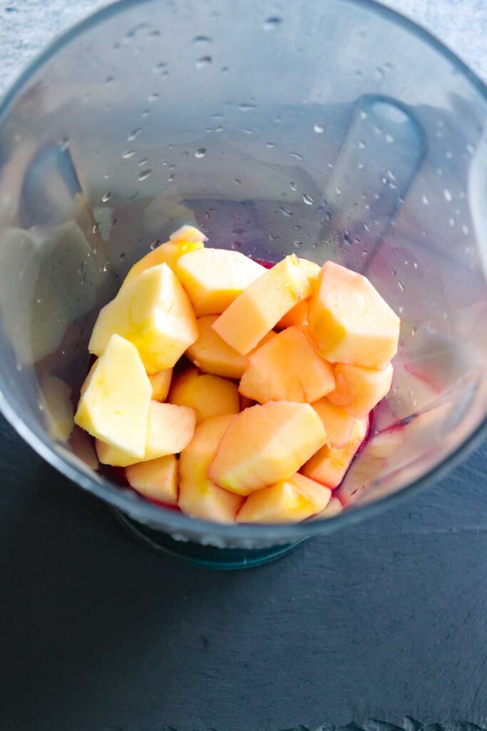 Blender Jar with peeled and cored apples, frozen banana and pomegranate juice