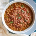 Instant Pot Brown Lentils Curry served in a white bowl with tempering of cumin seeds
