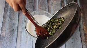 Adding the crispy sautéed okra to the yogurt mix