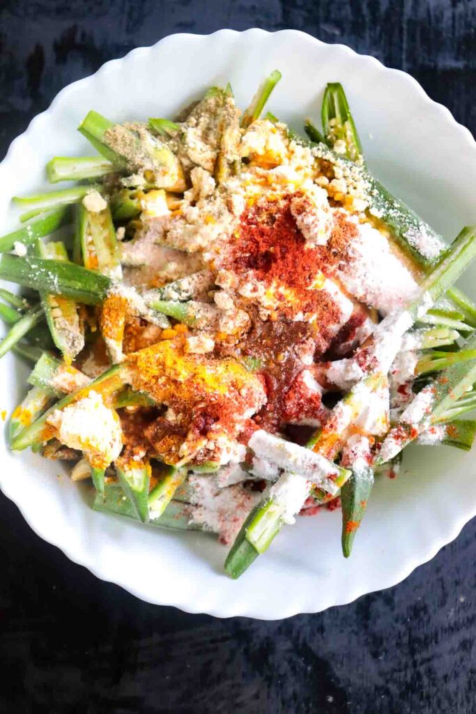 Flour and spices added to sliced okra for air frying Indian style fries