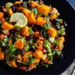 Vegan Black Bean Mango Salad served in a black bowl with lime wedges